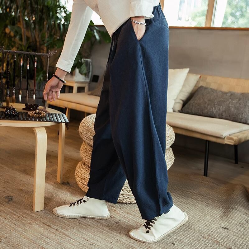 Person wearing navy wide-leg pants and white sneakers in a living room setting.