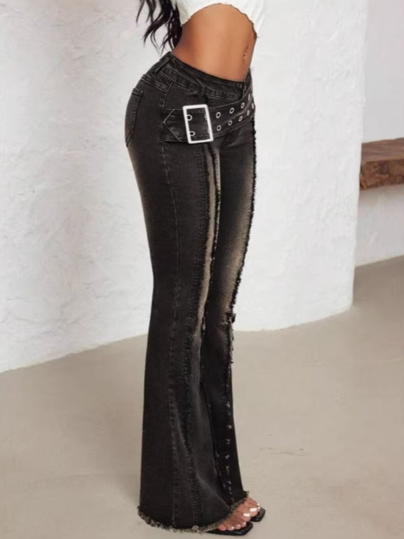 Black flared jeans with a silver buckle on a white background