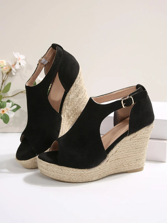 Black wedge sandals with espadrille soles on a light background