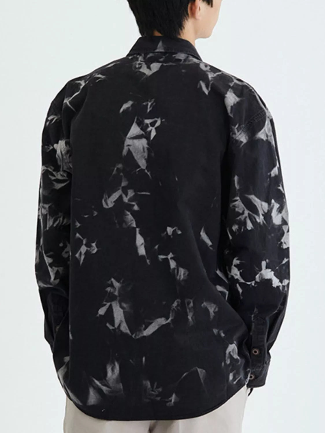 Person wearing a black floral patterned shirt on a white background