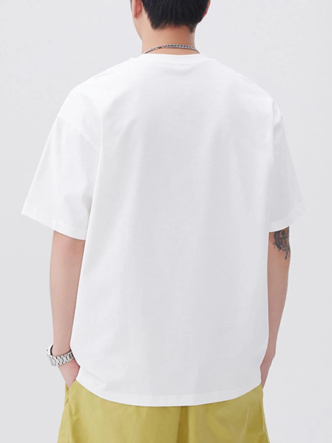 Person wearing a plain white t-shirt and light yellow pants on a white background