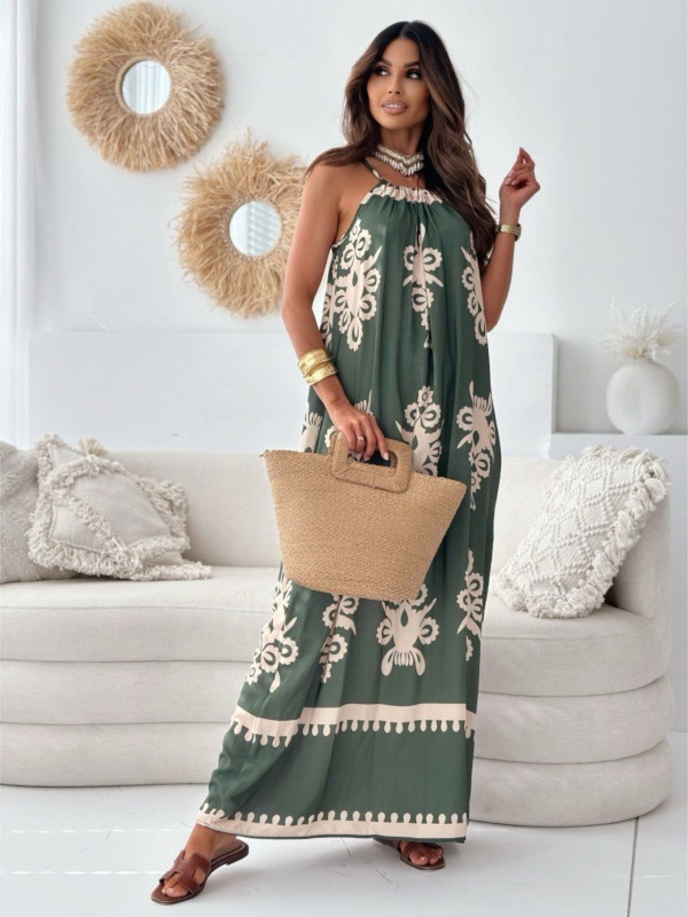 Woman in a green dress with white patterns holding a beige bag in a living room.