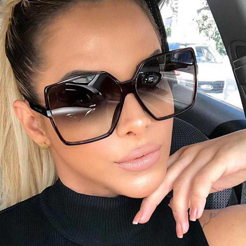 Person wearing large black sunglasses inside a vehicle