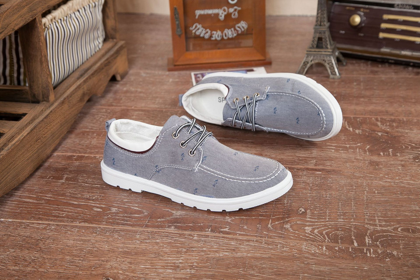 Pair of gray shoes with white soles on a wooden floor.