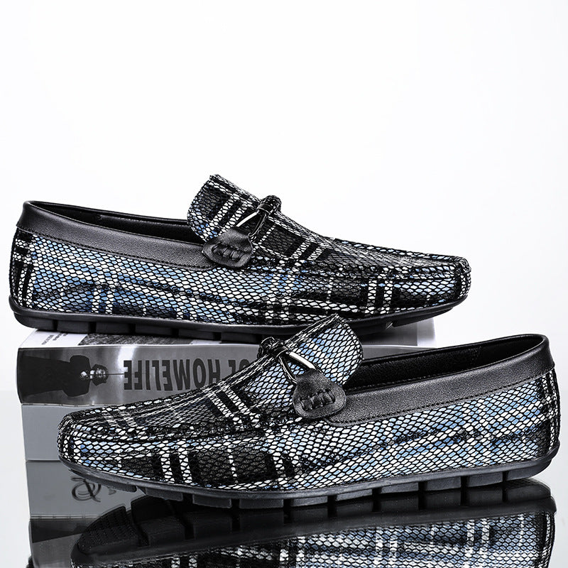 Black and silver patterned loafers on a reflective surface with a white background