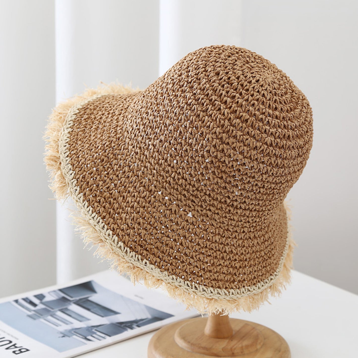 Heart-shaped straw hat on a wooden stand with a magazine in the background