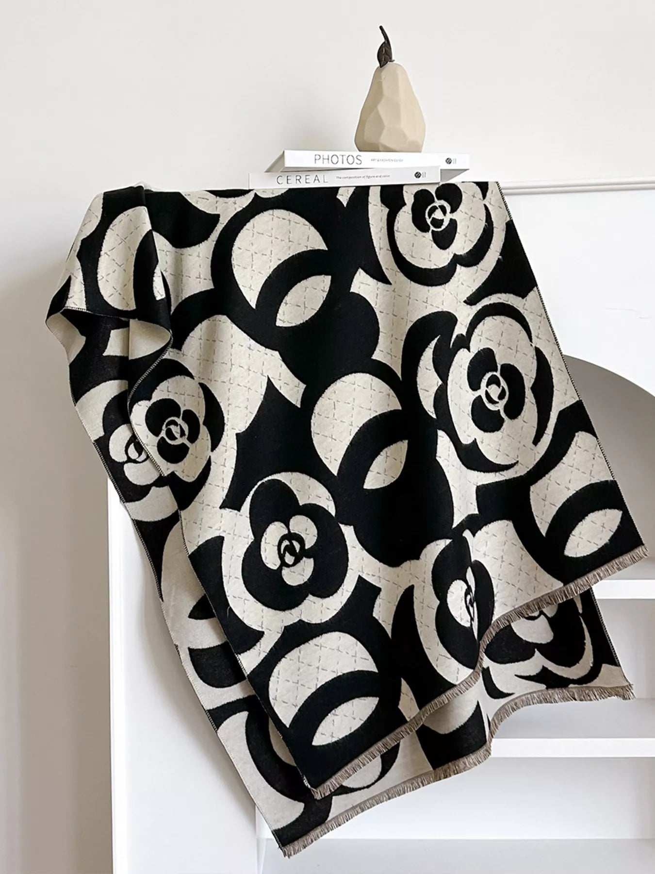 Black and white patterned blanket draped over a chair with a pear on top.