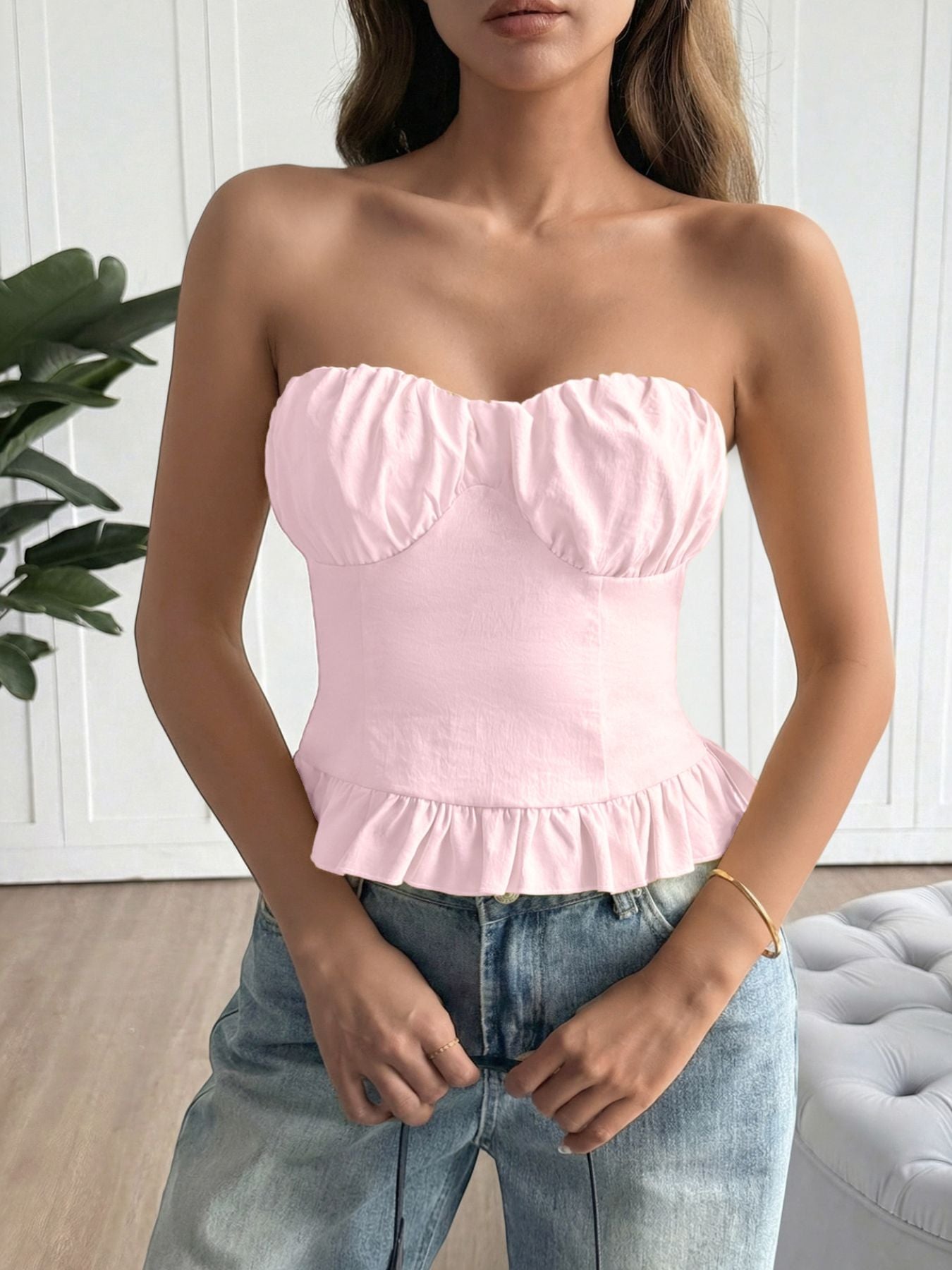 Woman wearing a pink strapless top and blue jeans indoors.