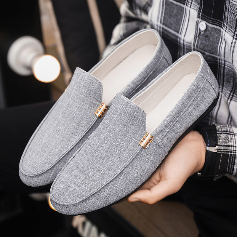 Gray loafers held by a person wearing a plaid shirt.