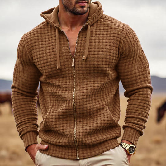 Man wearing a brown textured zip-up hoodie with a desert landscape in the background