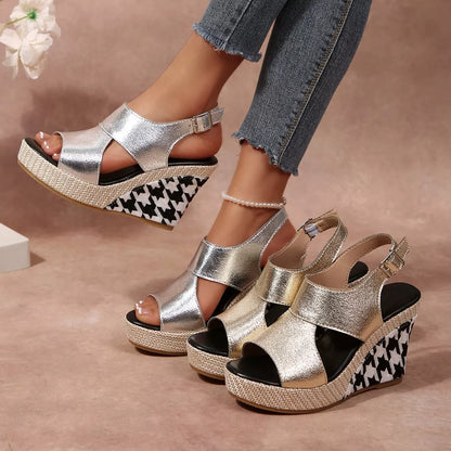 Silver wedge sandals with houndstooth pattern worn by a person, with a blurred floral 