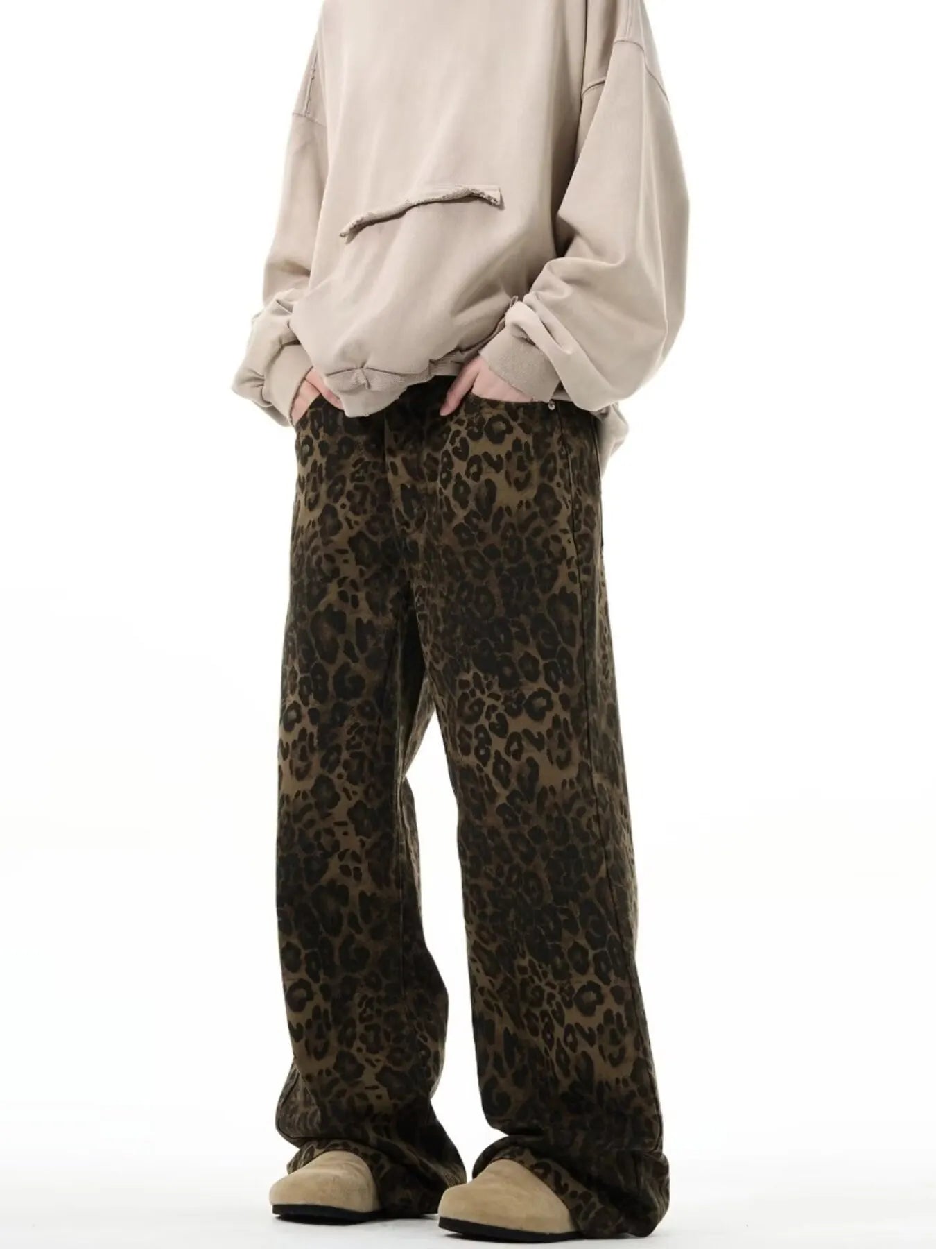 Person wearing a beige oversized sweatshirt and leopard print pants on a white background