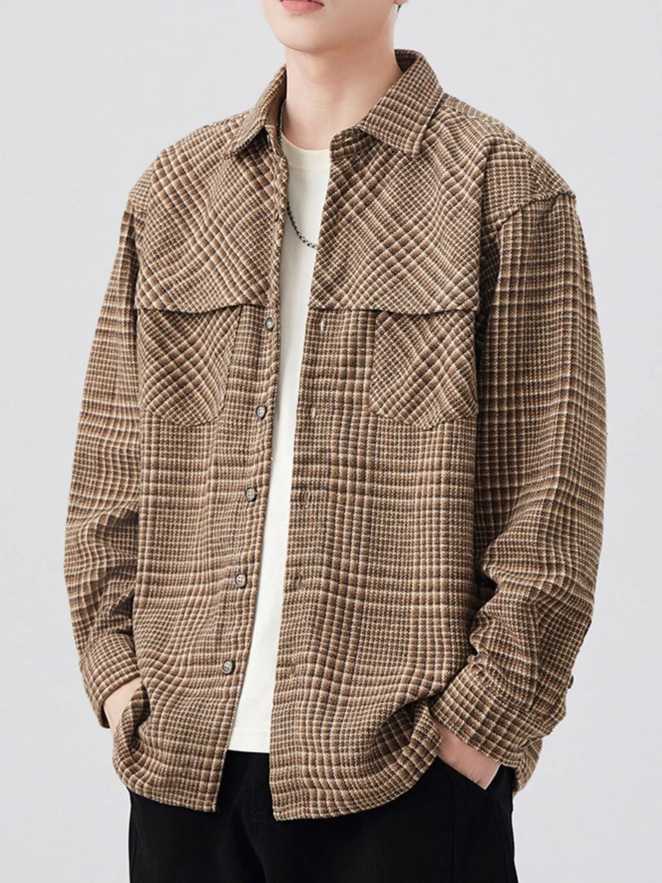 Person wearing a brown plaid shirt against a white background