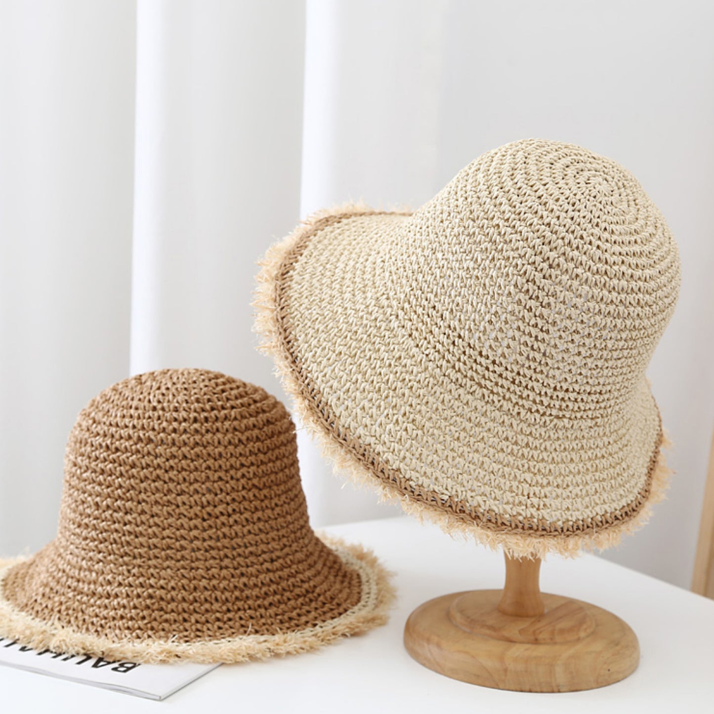 Two straw hats on a white surface with a neutral background