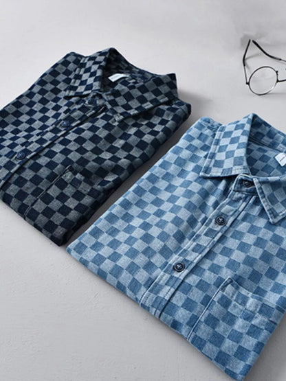 Two folded checkered shirts, one dark blue and one light blue, on a light gray surface.