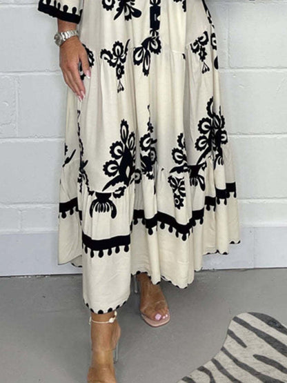 White dress with black floral patterns worn by a person against a white wall.