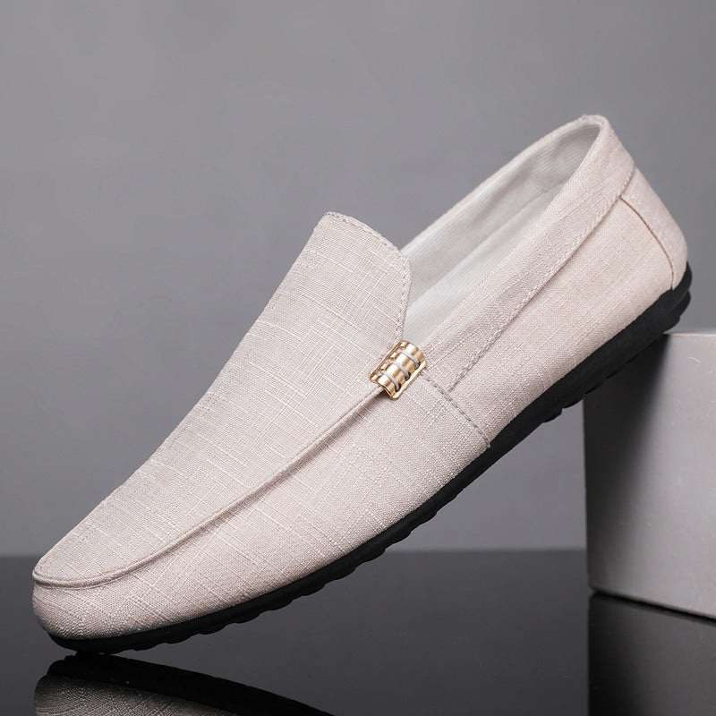 Light gray loafers with a gold buckle on a dark surface and gray background
