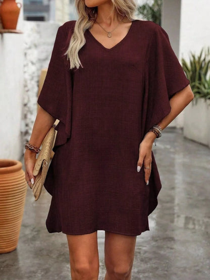 Woman wearing a burgundy dress with a neutral background