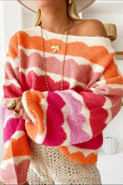 Person wearing a colorful off-shoulder sweater with pink, orange, and white pattern.
