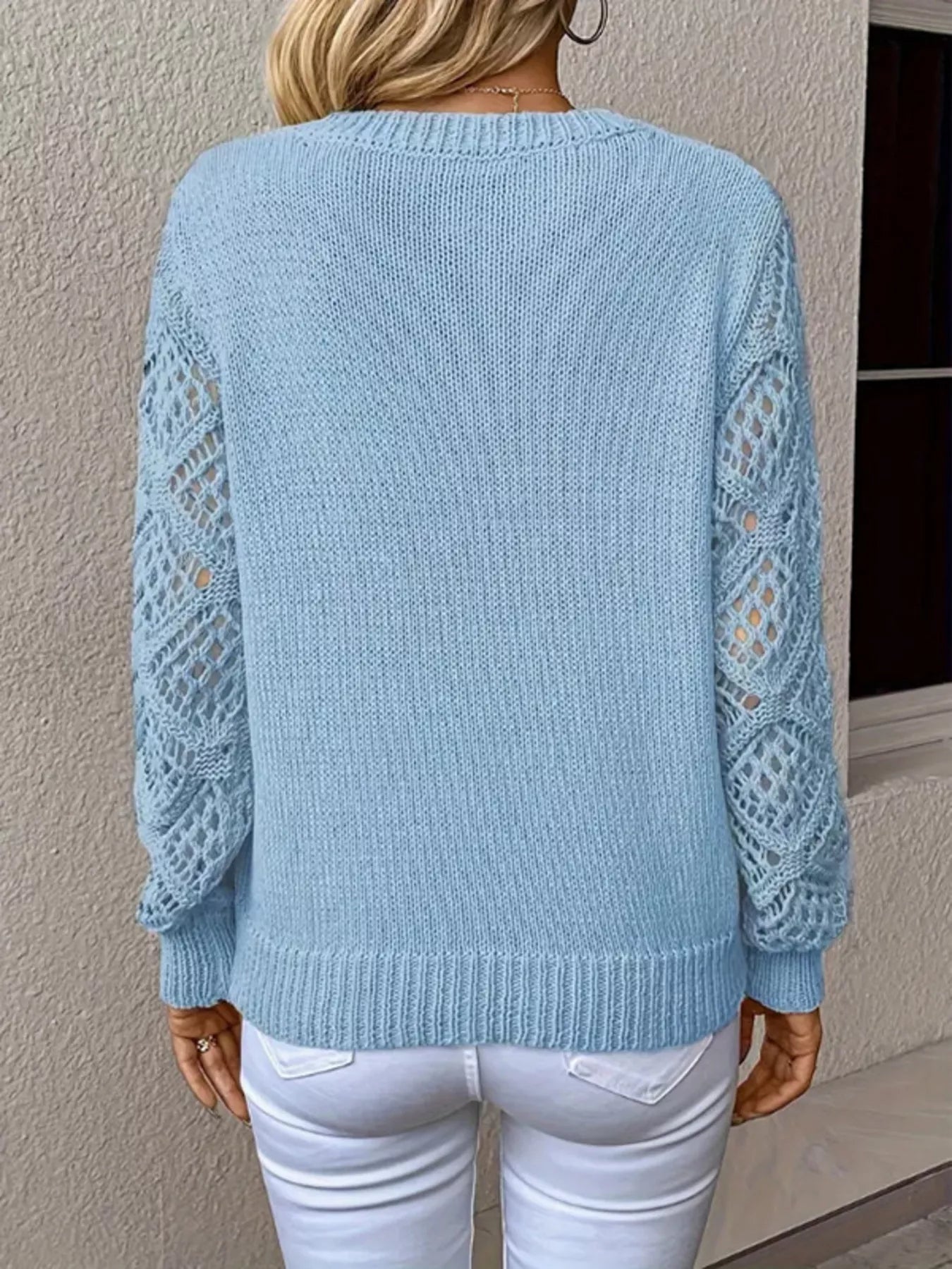 Light blue sweater with lace sleeves worn by a person against a neutral wall.