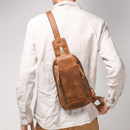 Person wearing a brown leather sling bag on a plain background