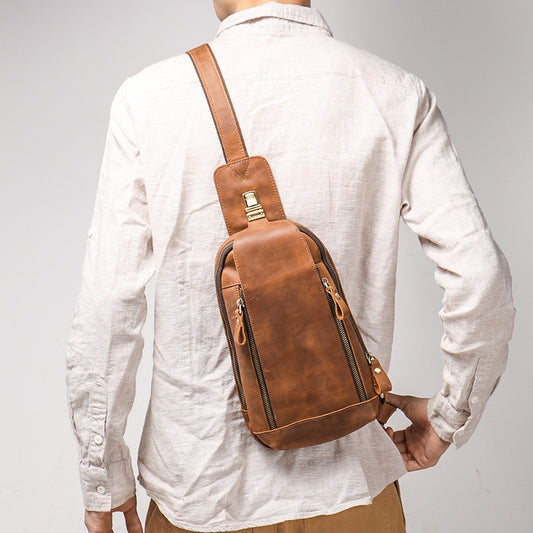 Person wearing a brown leather sling bag on a plain background