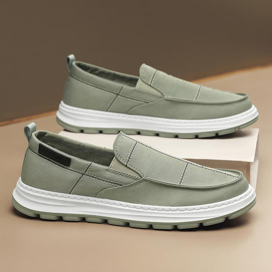 Pair of green loafers with white soles on a beige surface