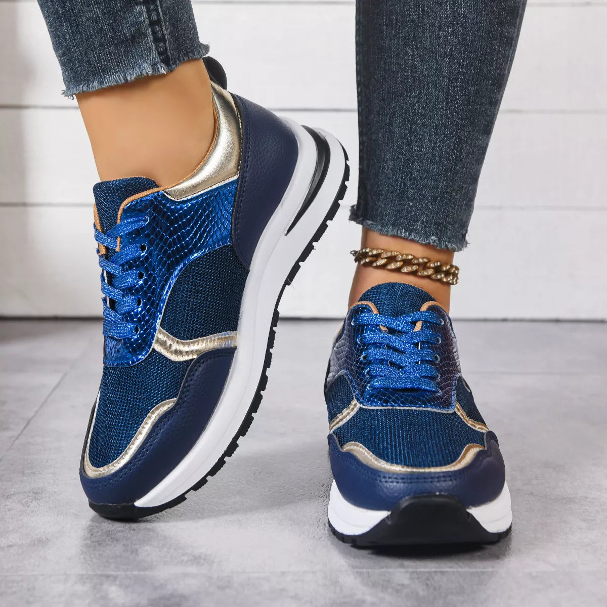 Blue and gold sneakers worn with jeans on a light background