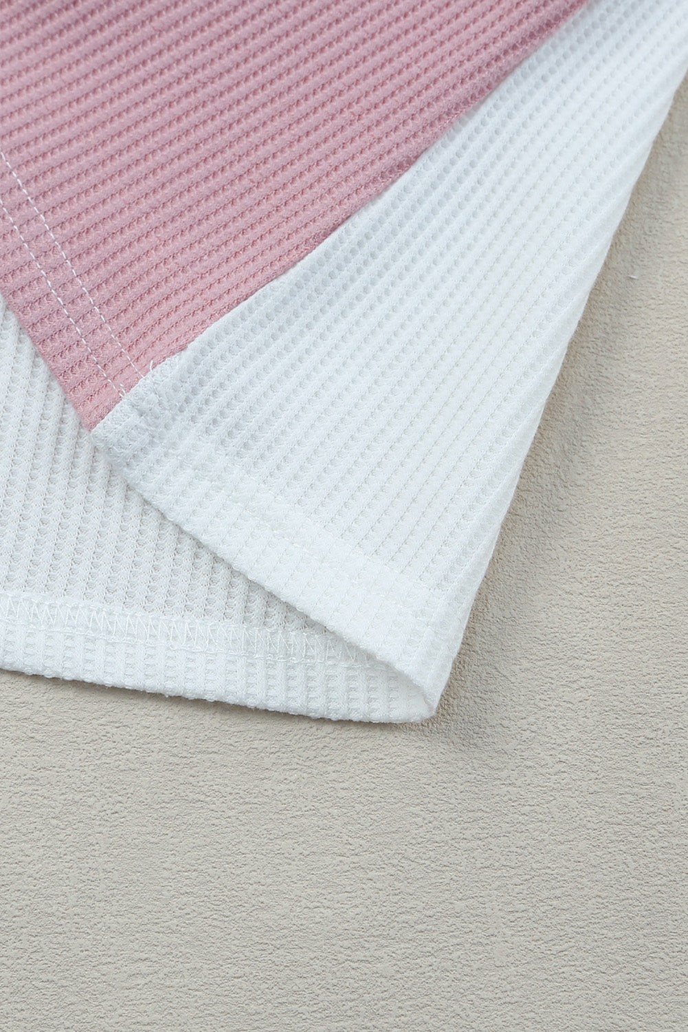 Close-up of a pink and white textured fabric on a beige surface