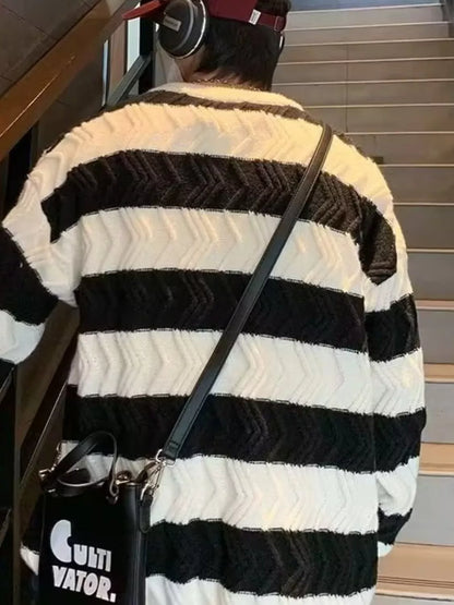 Person wearing a black and white striped sweater with a black bag, standing on stairs.