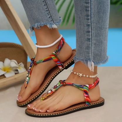 Colorful sandals with decorative straps worn with denim jeans on a blurred background