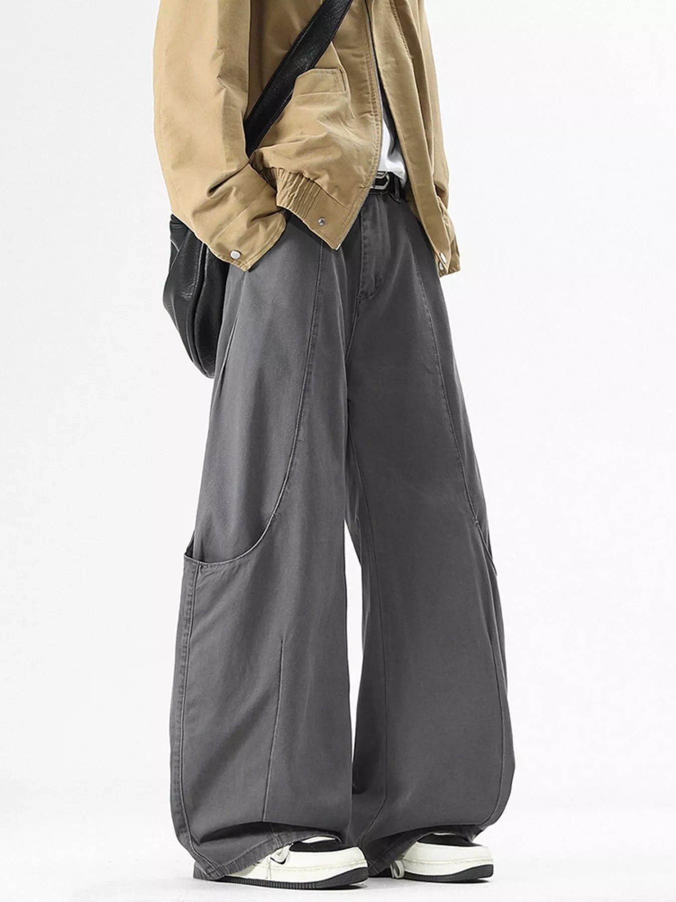 Person wearing a beige jacket and gray wide-leg pants on a white background