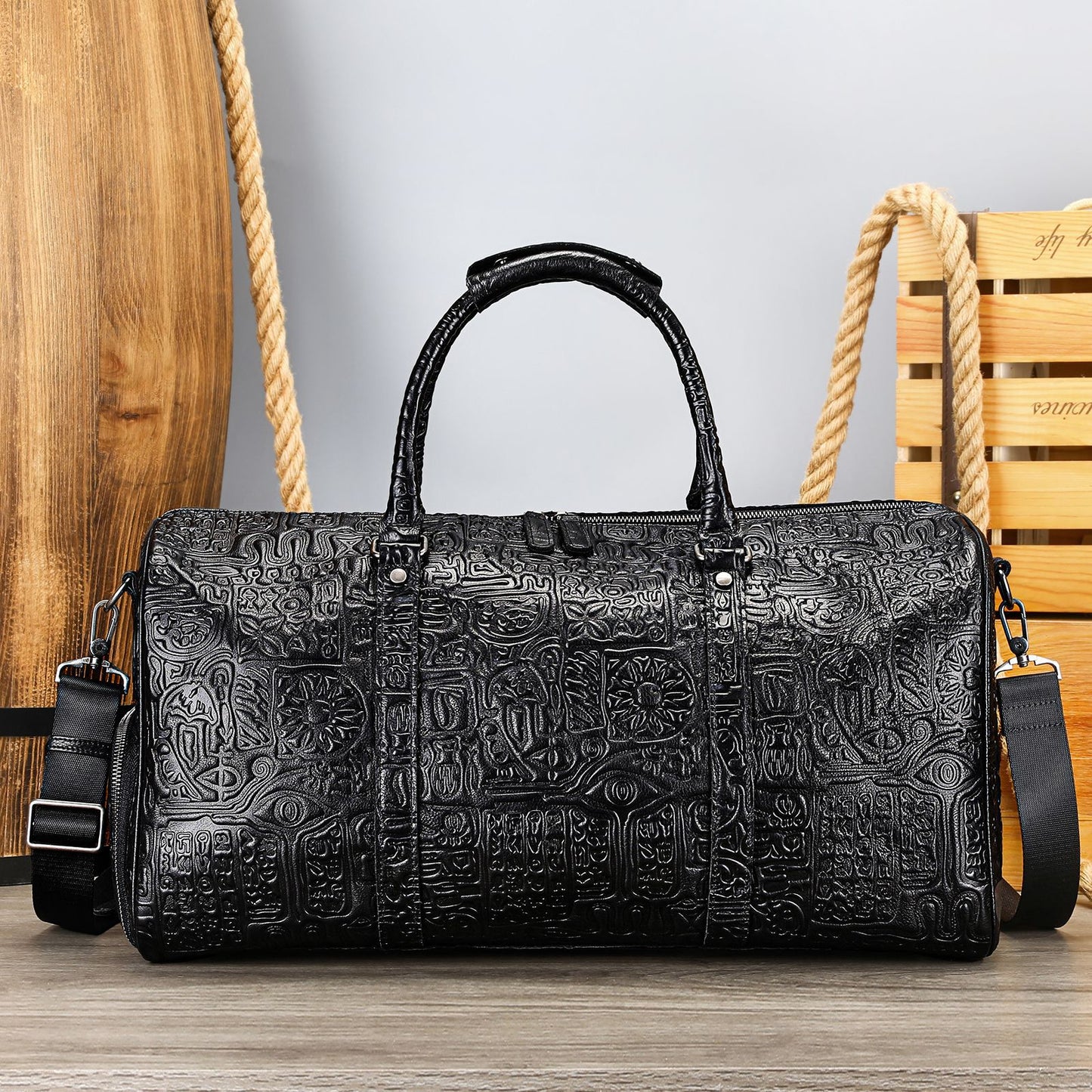 Black textured duffel bag on a wooden surface with a wooden chair in the background