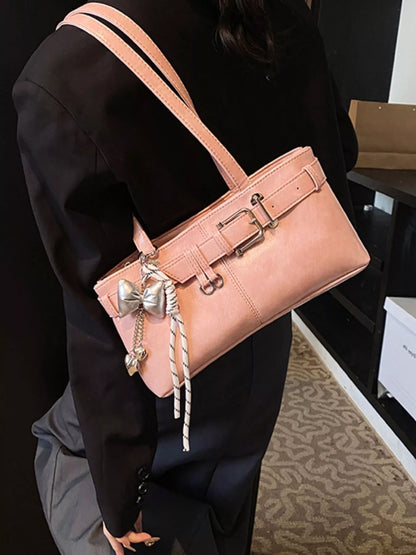 Person holding a pink handbag with decorative elements in an indoor setting