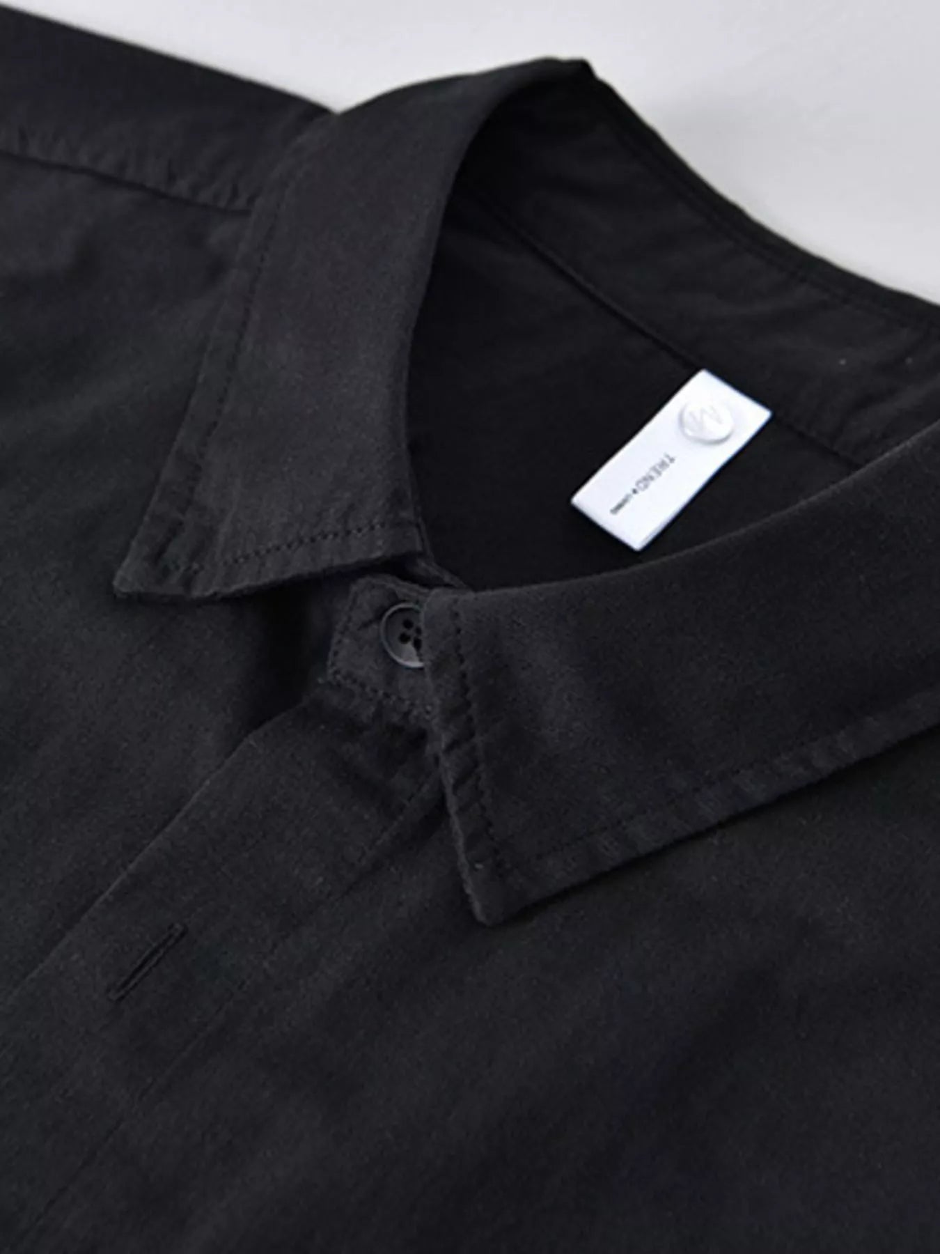 Black shirt with a visible brand label on a light gray background