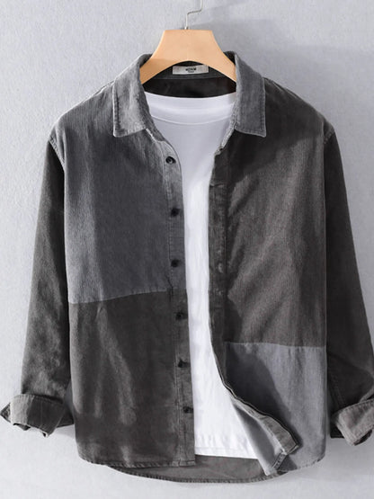 Gray denim shirt over a white t-shirt on a hanger against a gray background