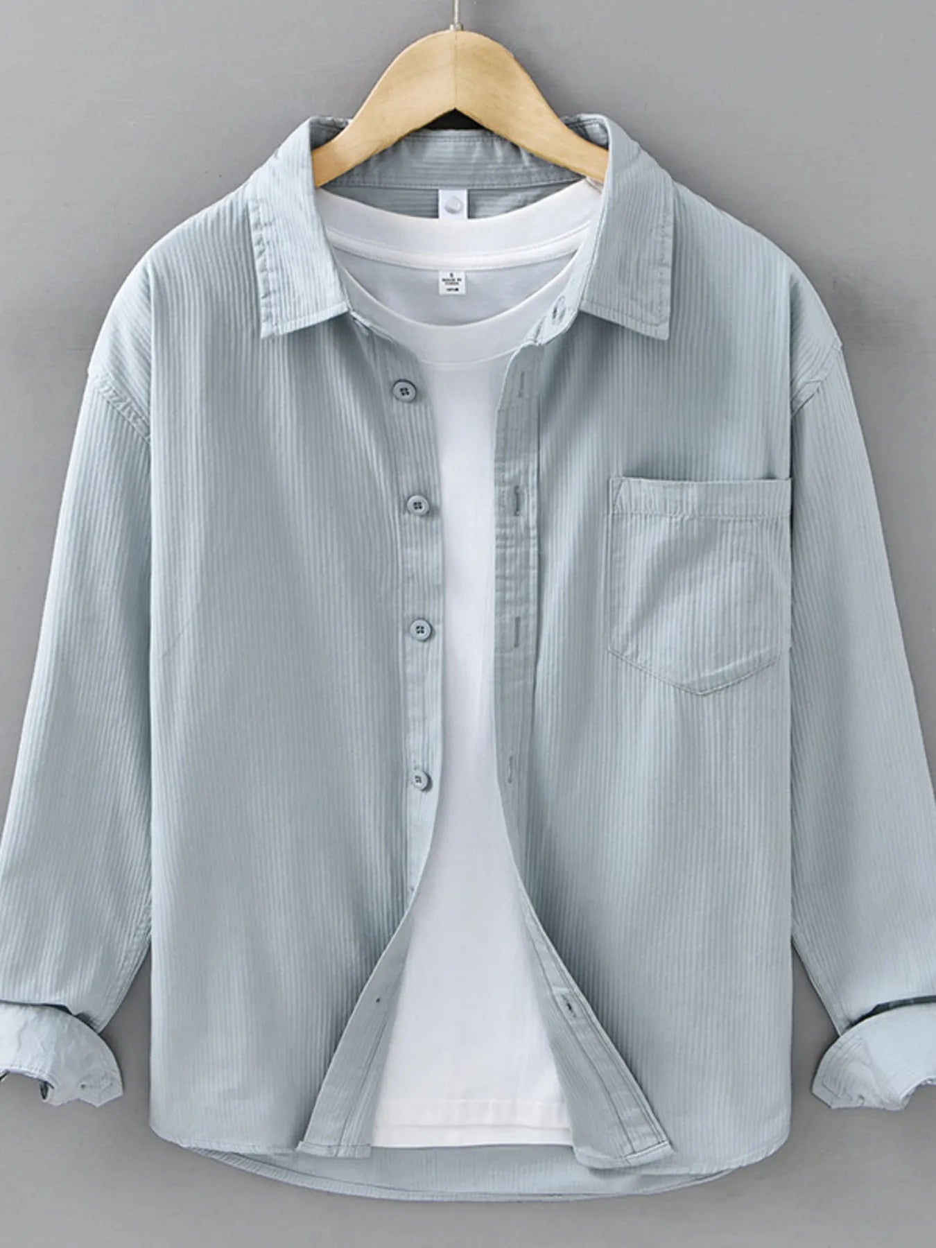 Light blue corduroy shirt on a hanger against a gray background