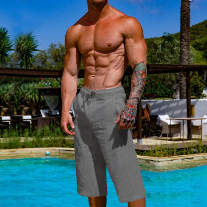 Man in gray shorts standing by a pool with a scenic background