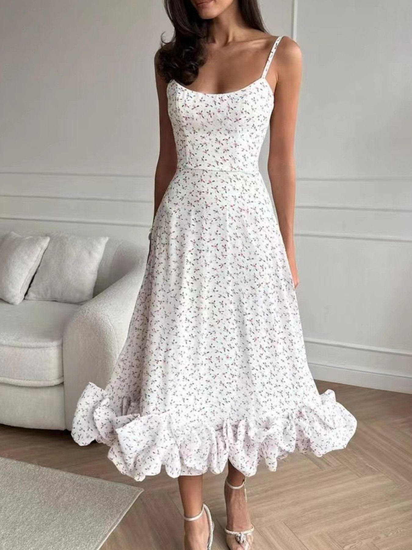 Woman wearing a white floral dress in a room with a gray sofa.