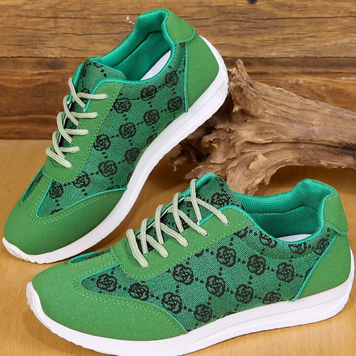 Green sneakers with black floral patterns on a wooden surface