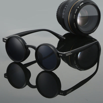 Black eyeglasses with a camera lens on a reflective gray surface