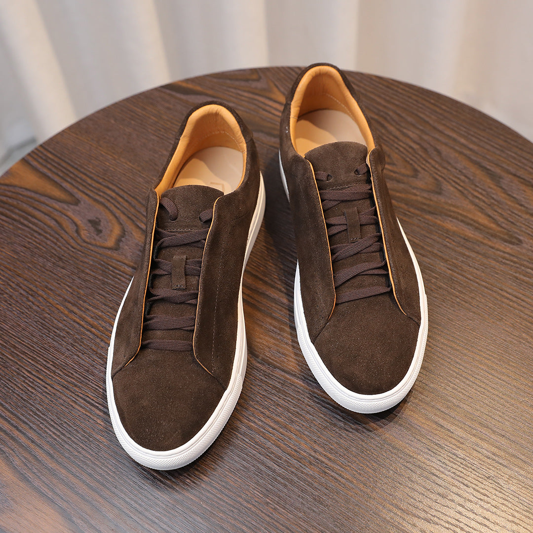 Brown suede shoes with white soles on a wooden surface
