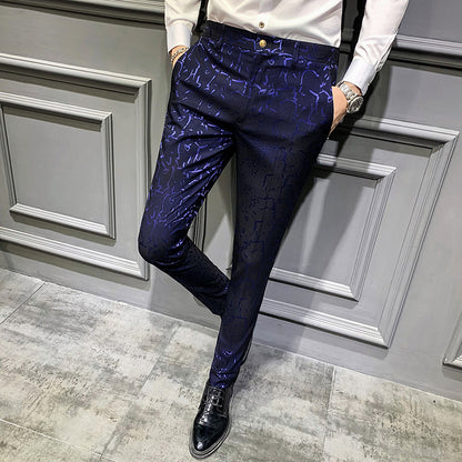 Person wearing a white shirt and blue patterned pants against a gray paneled wall.