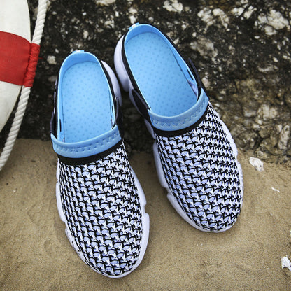 Pair of black and white patterned shoes with blue soles on a sandy surface.