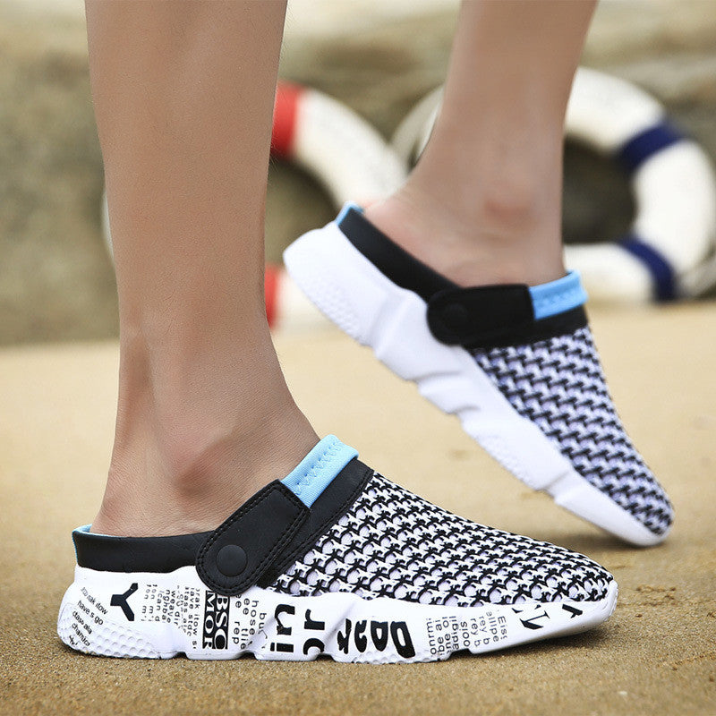 Black and white patterned clogs with blue accents worn on a sandy surface.