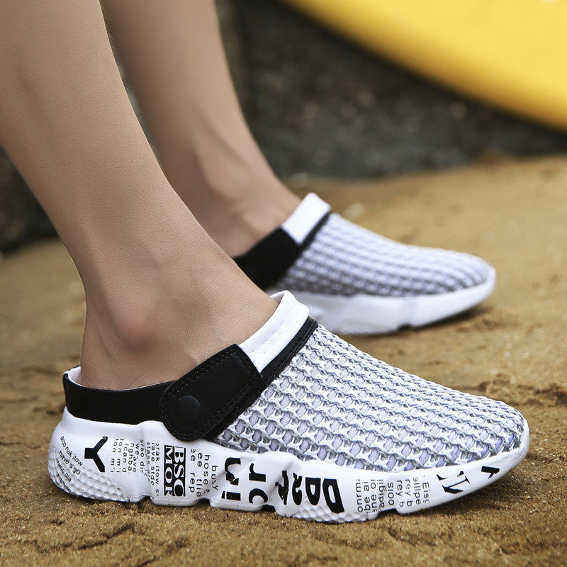 White and black clogs with text on a sandy surface