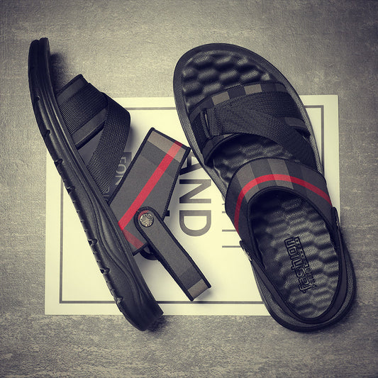 Black sandals with red accents on a textured surface
