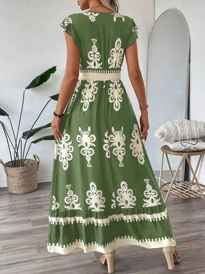 Woman wearing a green dress with white lace patterns in a room.