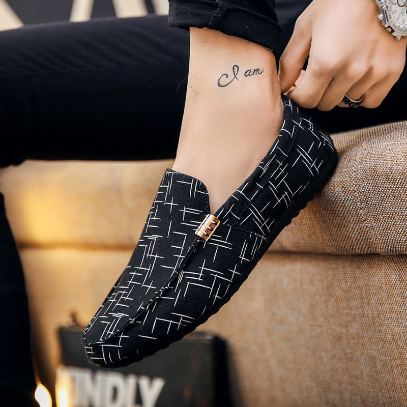 Person wearing black patterned loafers with a tattoo on their arm.