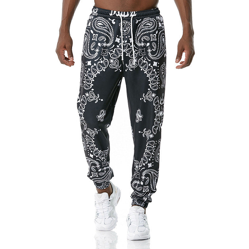 Black jogger pants with white bandana pattern worn by a person on a white background